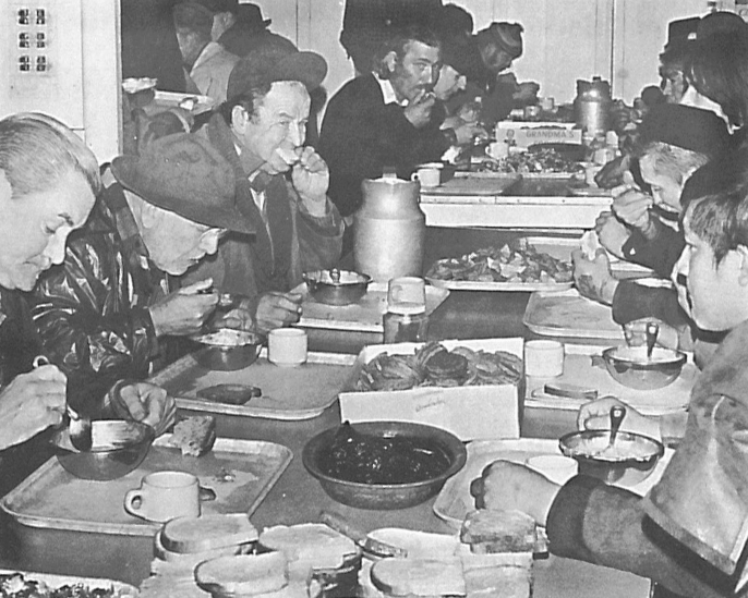black and white image of diverse people eating around a table